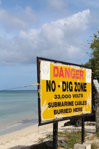 Warnschild an der Cable Bay auf Tobago in Trinidad und Tobago in der Karibik. Hier kommt eine Versorgungsleitung mit Strom an Land an. Das Schild warnt davor das Kabel zu zerstören oder beschädigen.